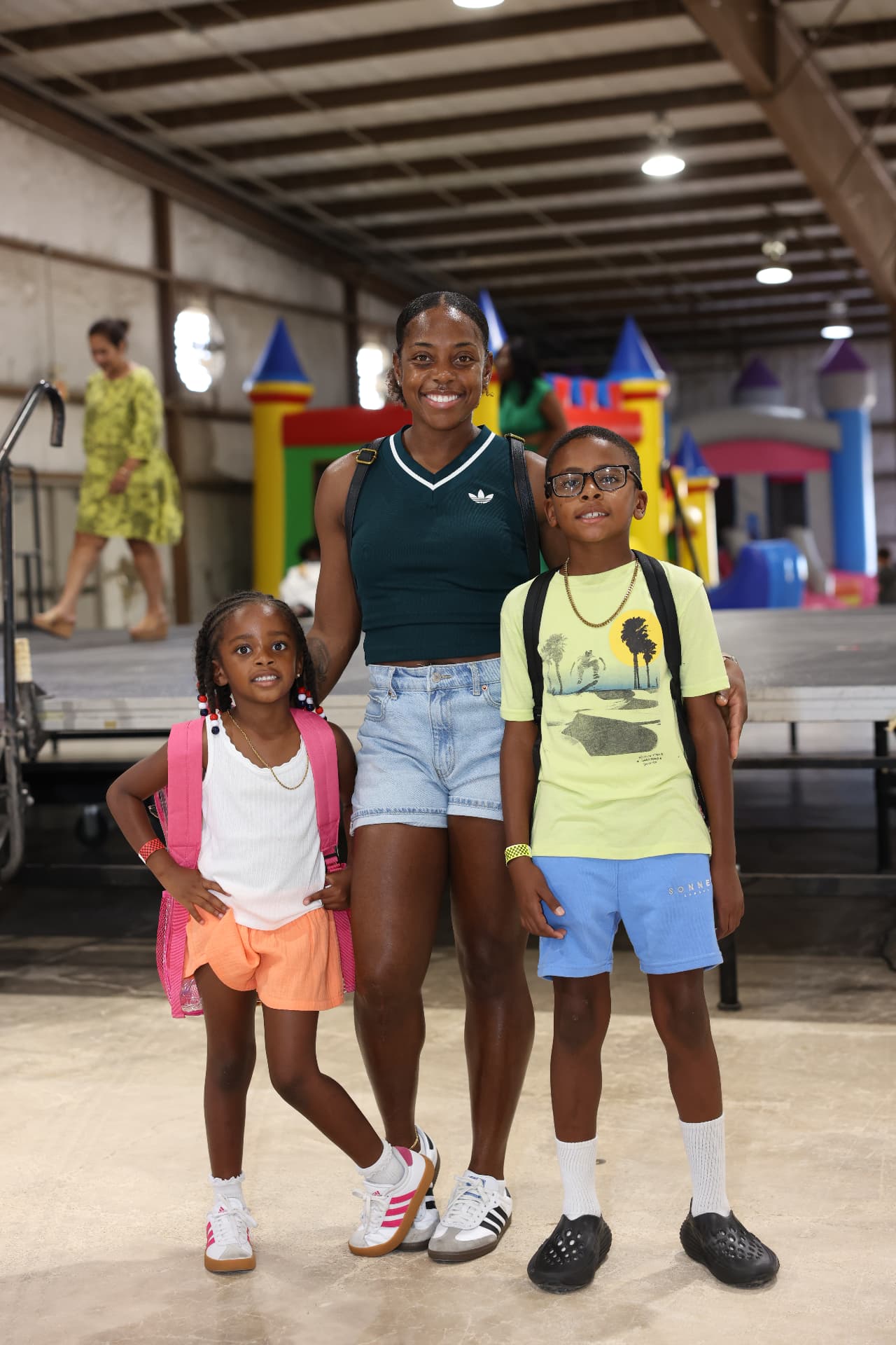 A mother with her son and daughter in front of the bounce houses.