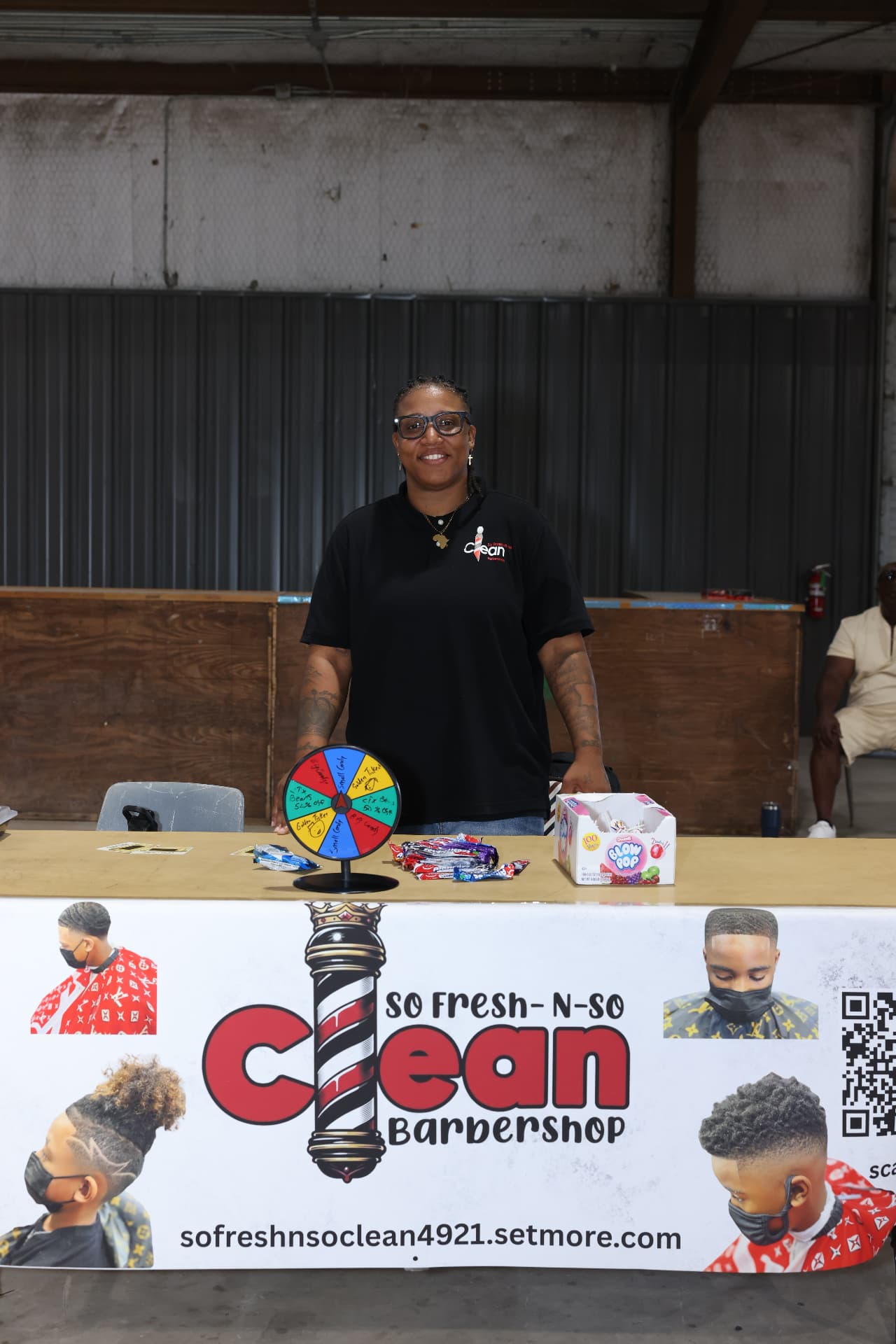 A So Fresh-N-So Clean Barbershop volunteer at her prize wheel and candy table.