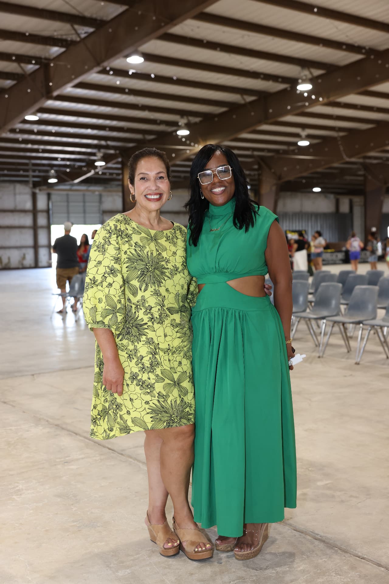 Two organizers smiling together inside the venue before the program begins.