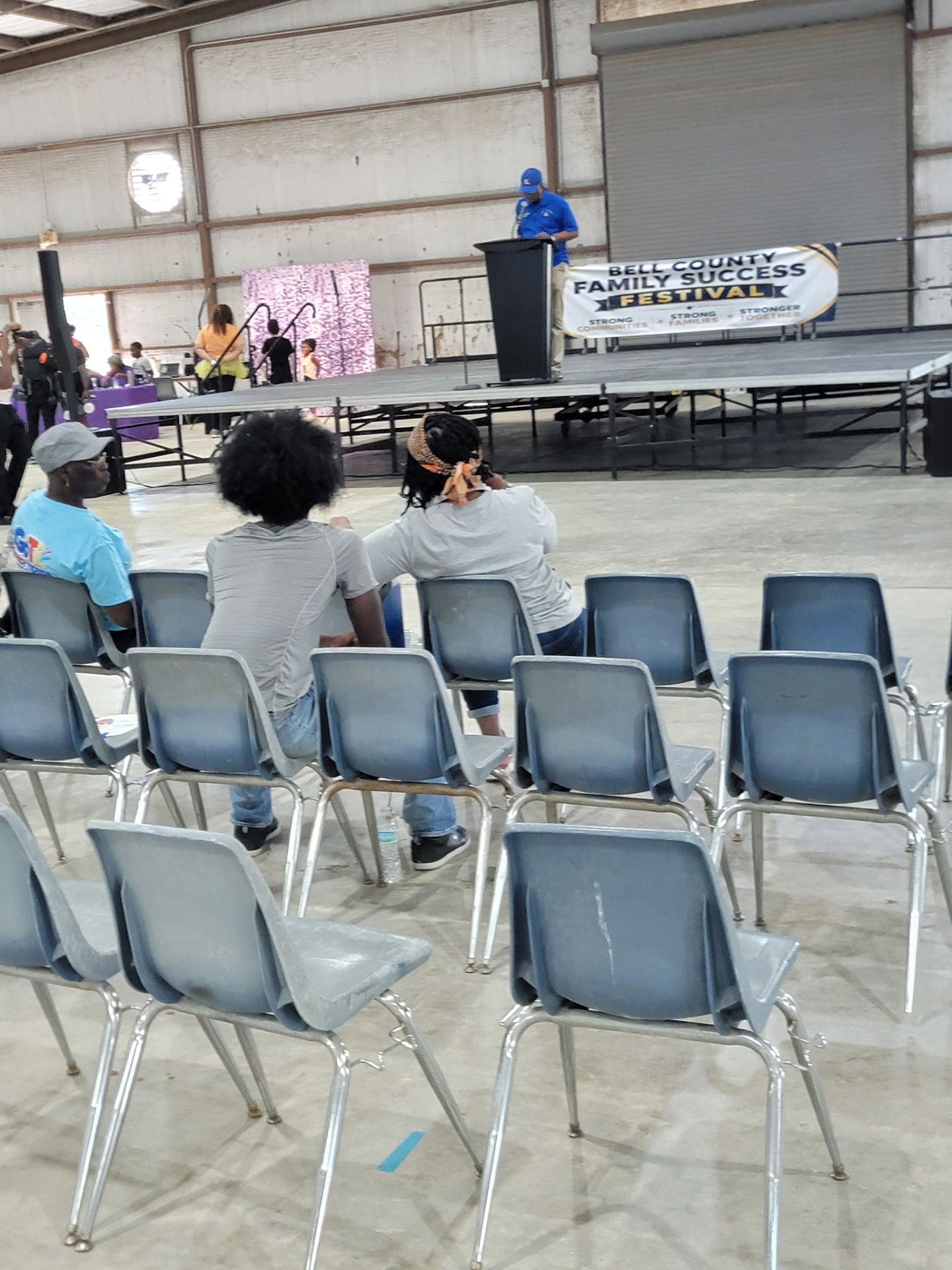 Families seated in front of the stage as a speaker welcomes the crowd.
