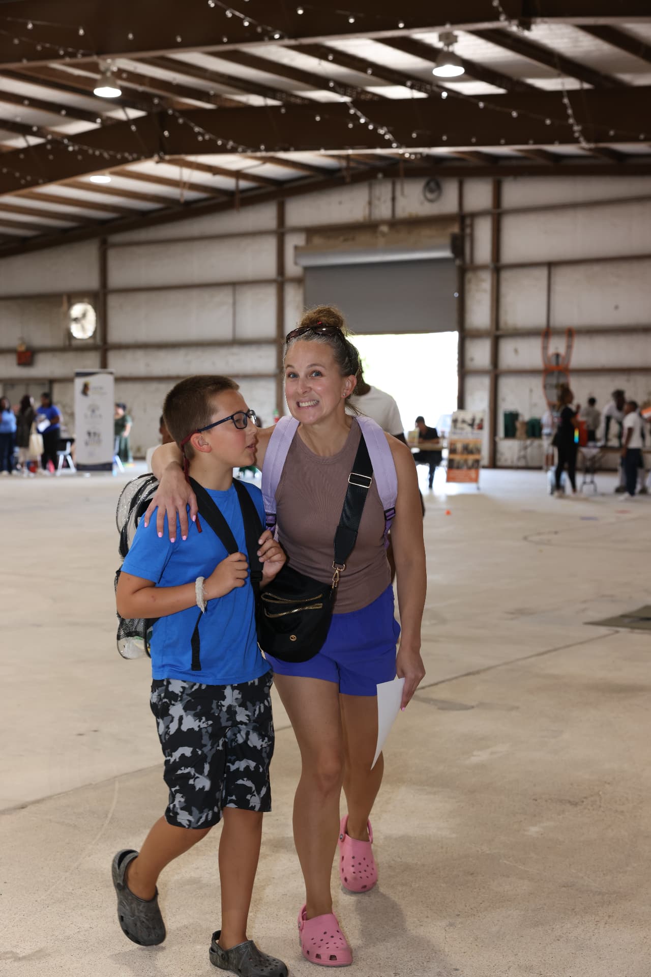 A mother and son walking together, the son wearing a mesh backpack.