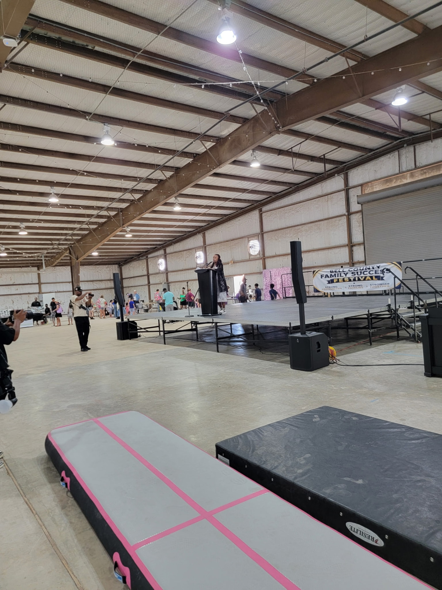 Wide view of the community stage with a speaker and the festival banner.