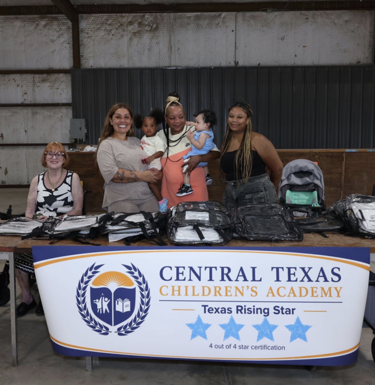 Central Texas Children's Academy team and families behind a table of clear backpacks.