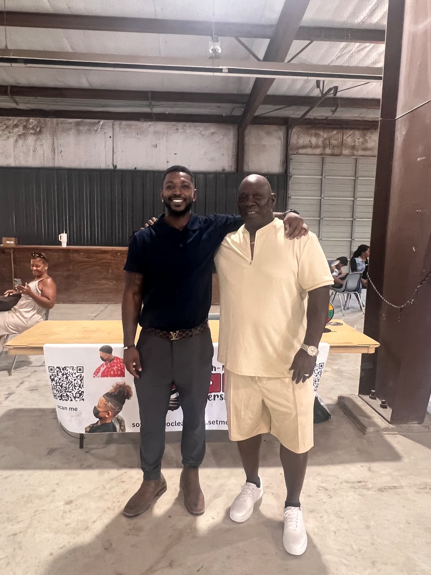 The festival organizer with a community elder at the So Fresh-N-So Clean Barbershop table.