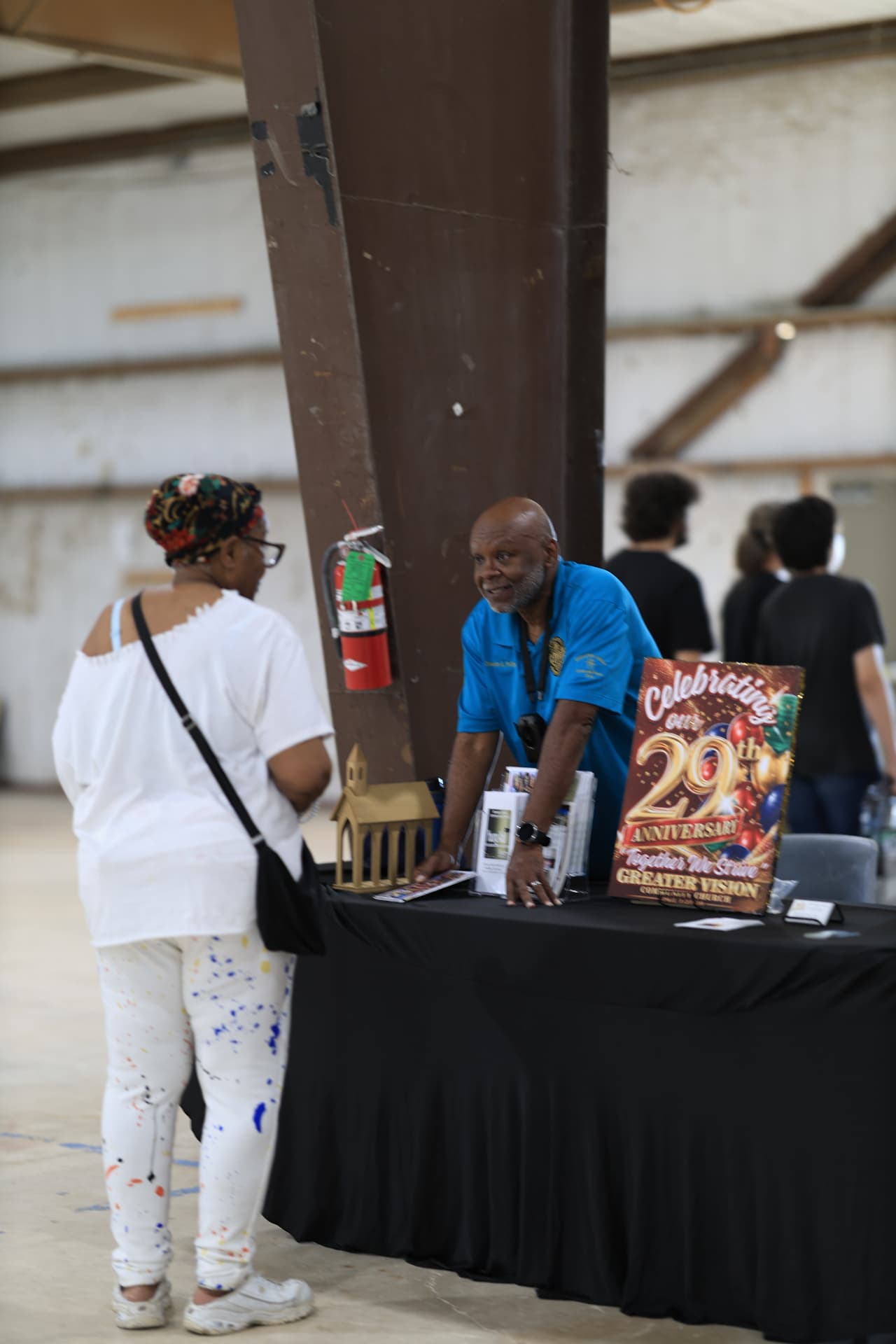 A Greater Vision Community Church volunteer speaking with a visitor at their table.
