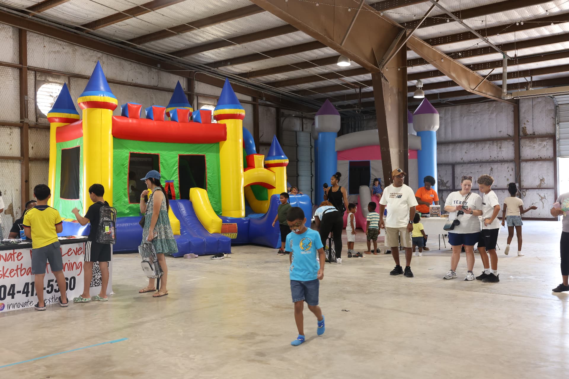 Children and families around the bounce houses and partner booths.
