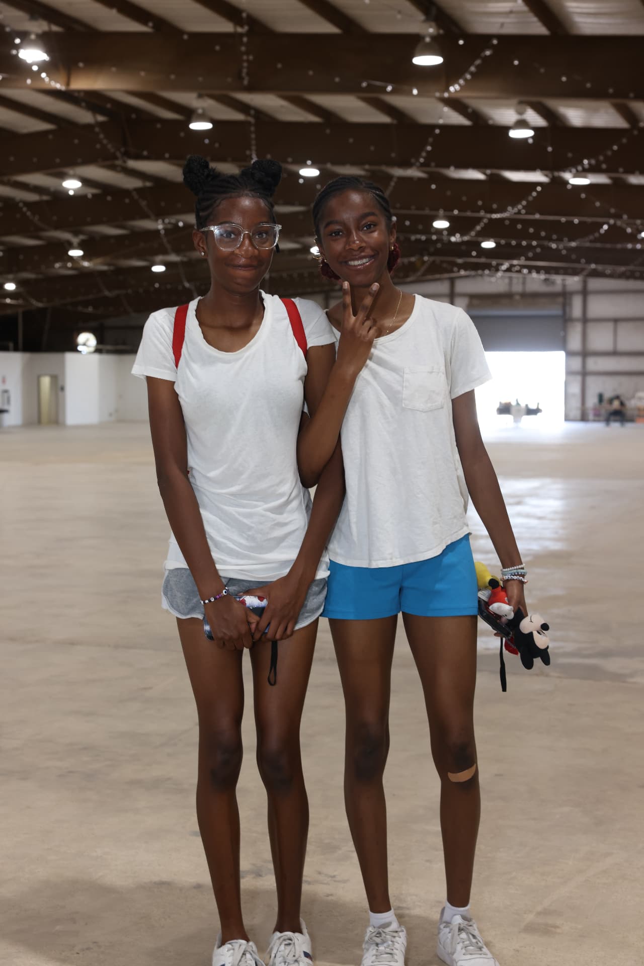 Two teen girls smiling together inside the festival hall.