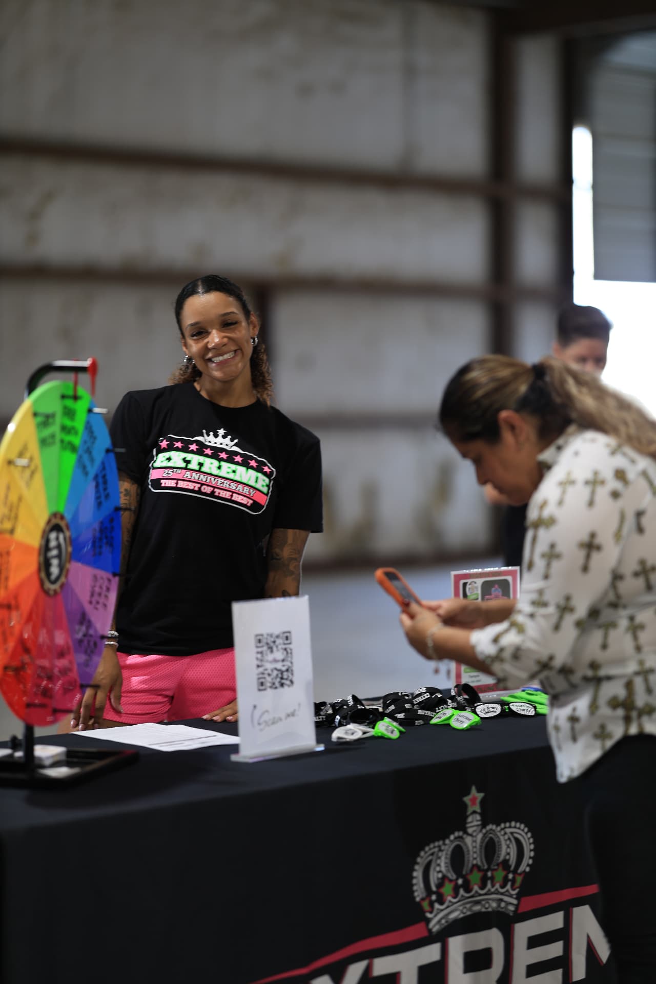 An Extreme Gymnastics coach greeting a visitor at the prize wheel table.
