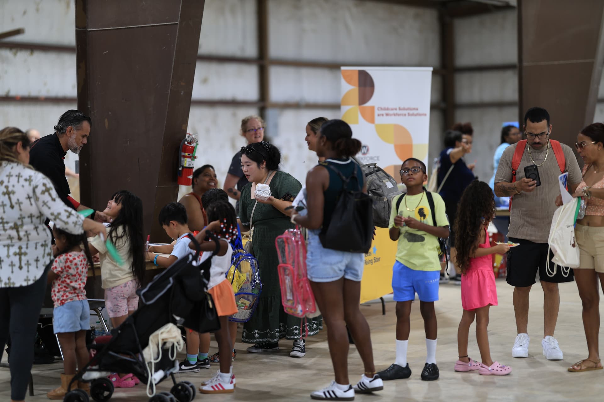 Families with clear backpacks visiting resource booths inside the venue.