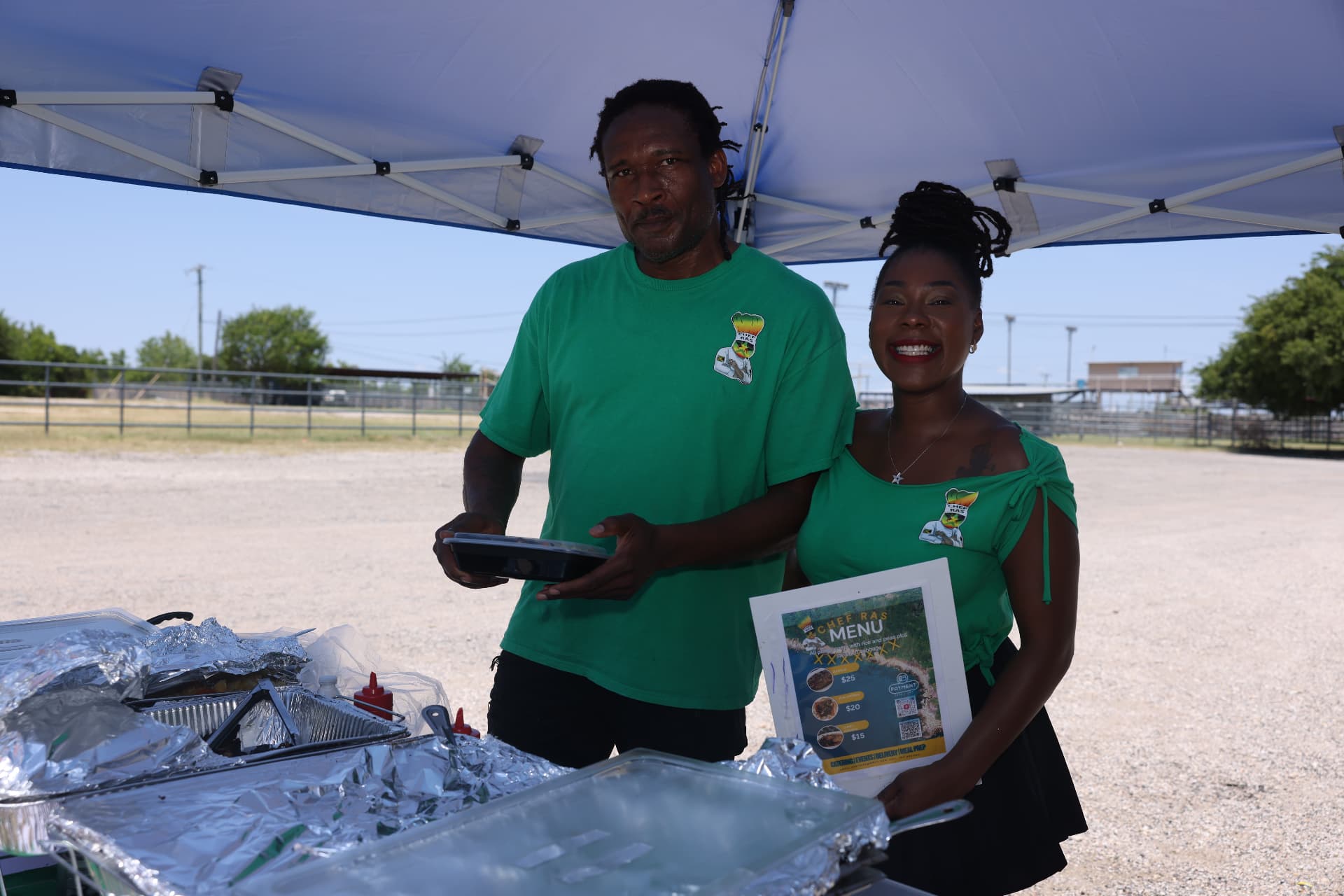 The Chef Ras team smiling with their menu at the food vendor booth.