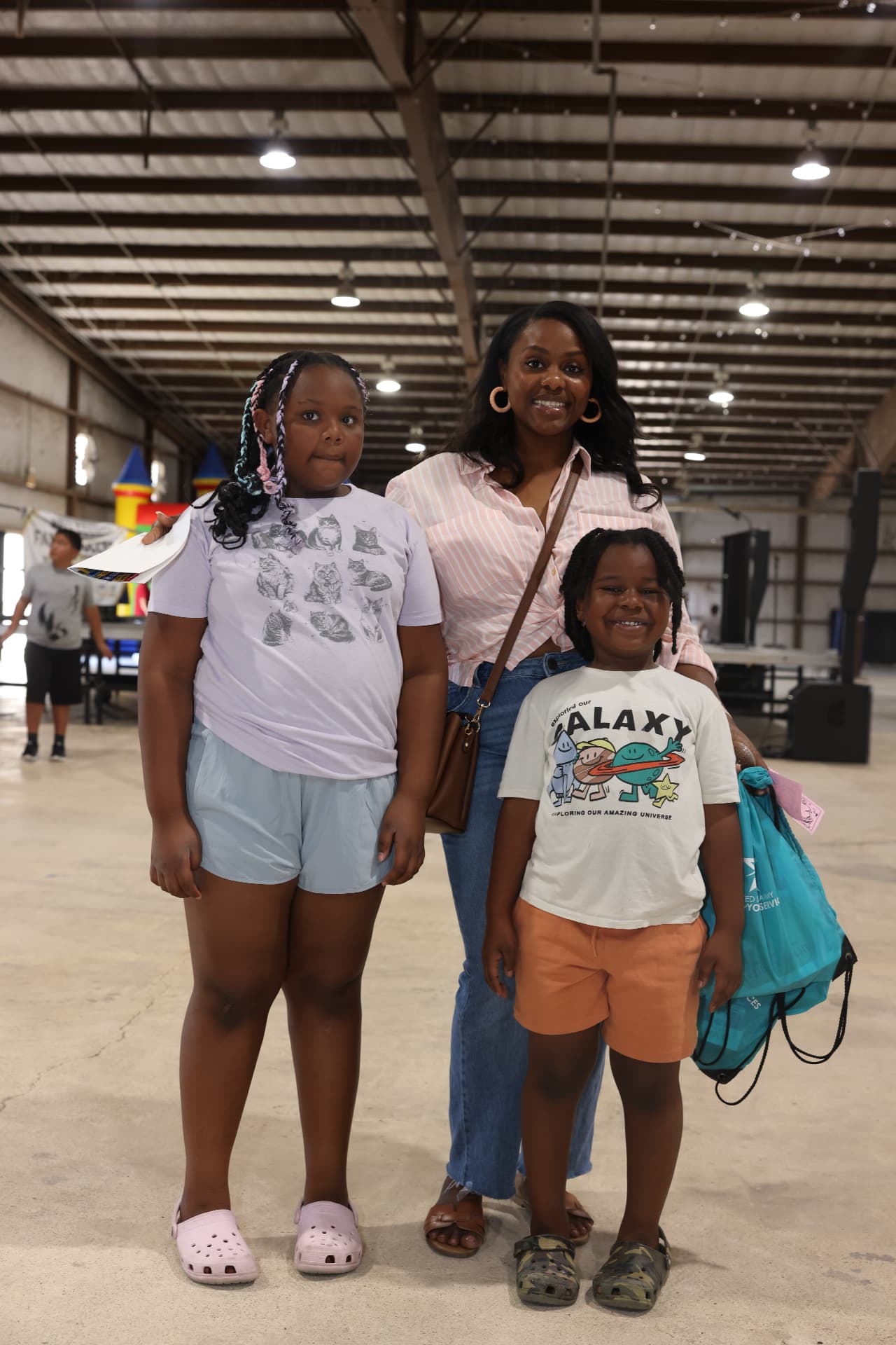 A mother with her two children holding giveaway bags at the festival.
