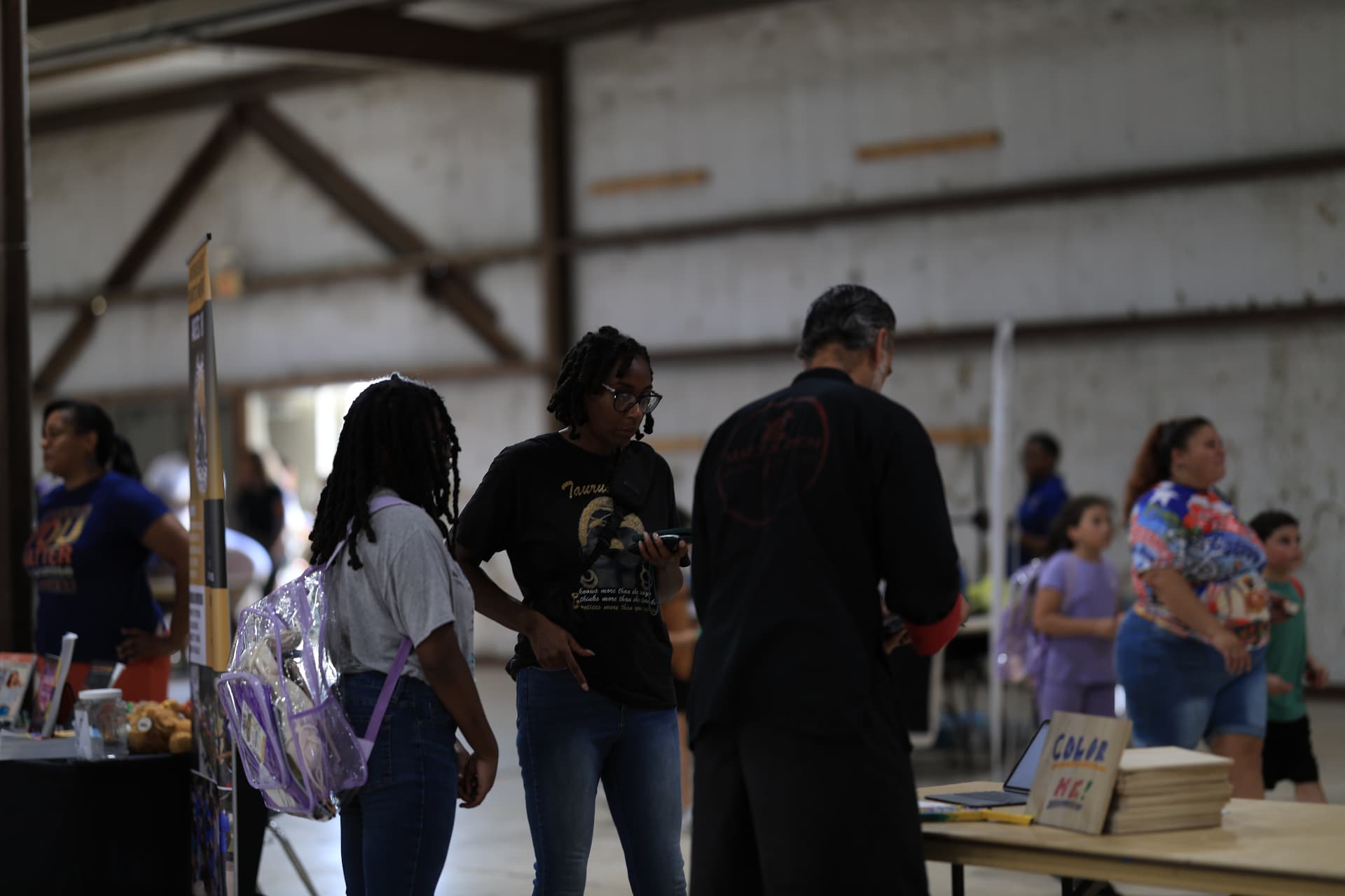 A teen with a clear backpack visiting a resource table with her mother.
