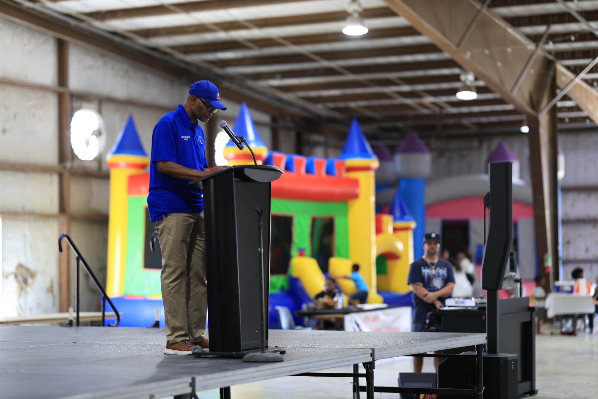 Mayor Joseph Solomon at the podium with bounce houses in the background.