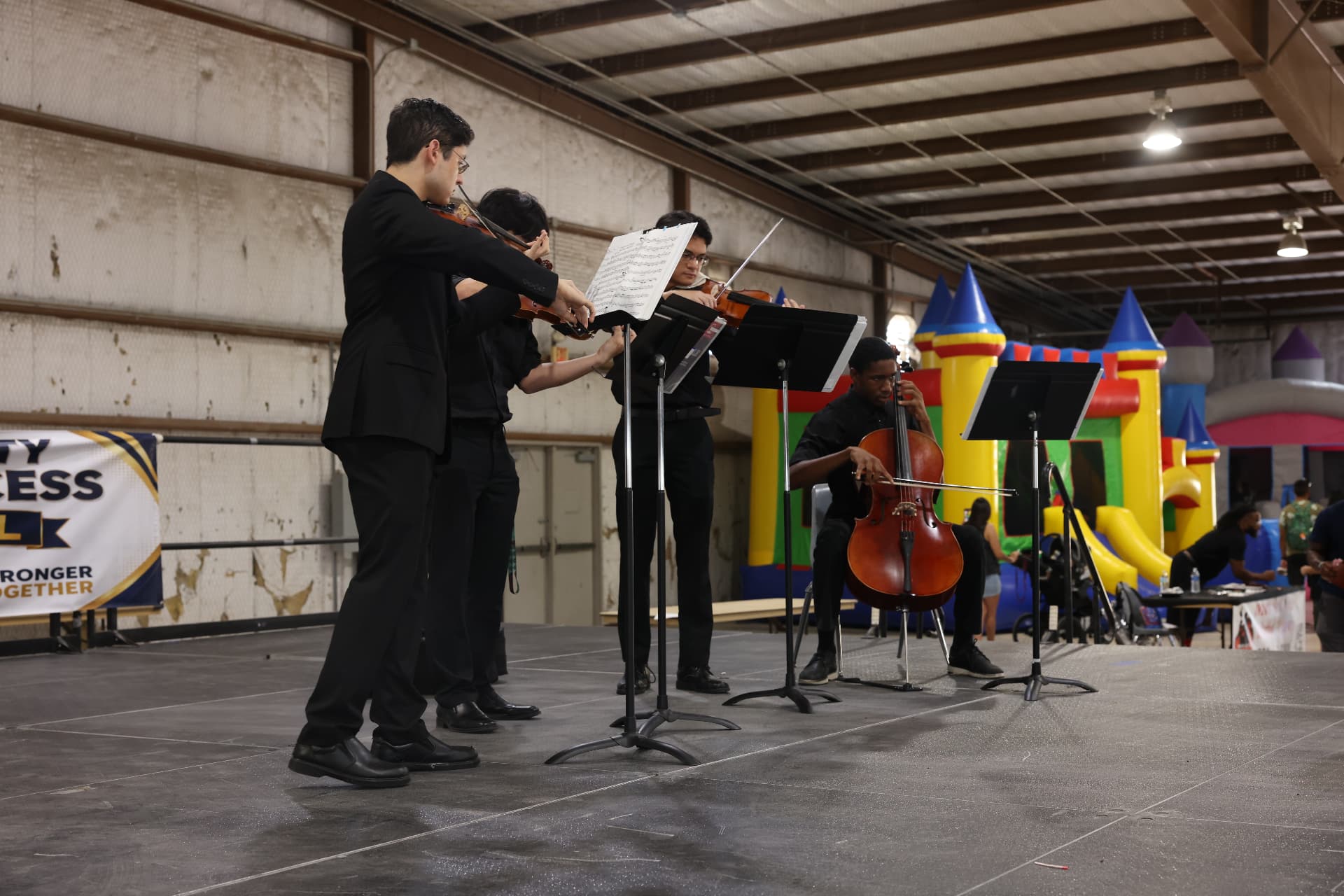 A student string quartet performing beside the festival banner.
