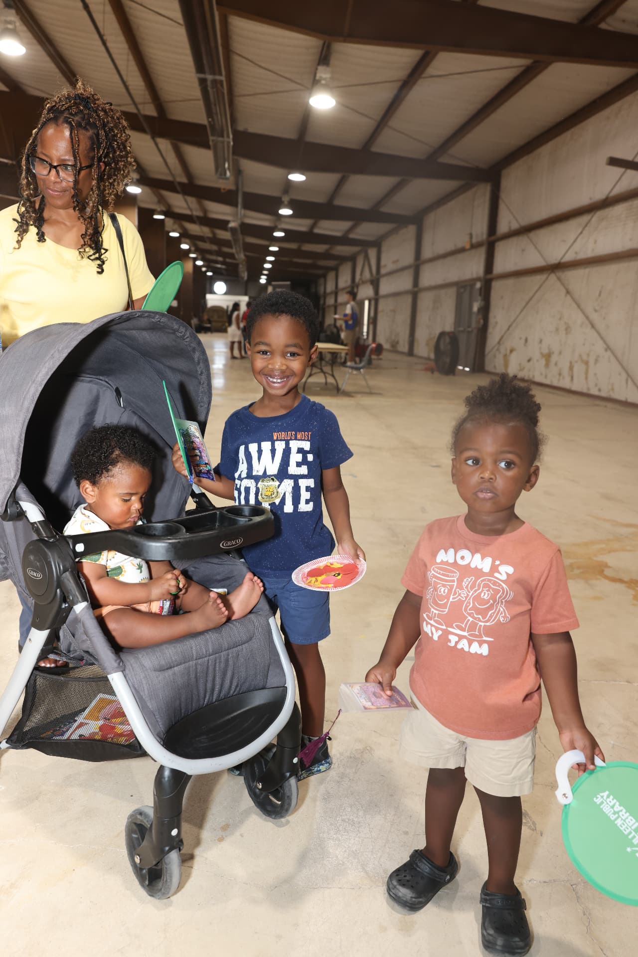 A mother with three young children carrying giveaways and library fans.
