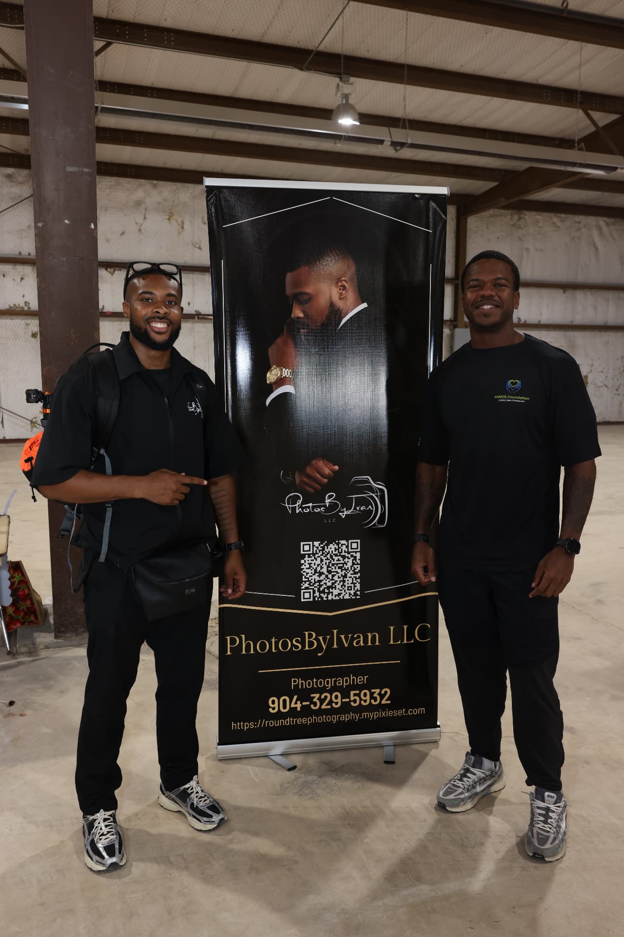 Photographer from PhotosByIvan LLC with an HWDS Foundation volunteer beside the photography banner.