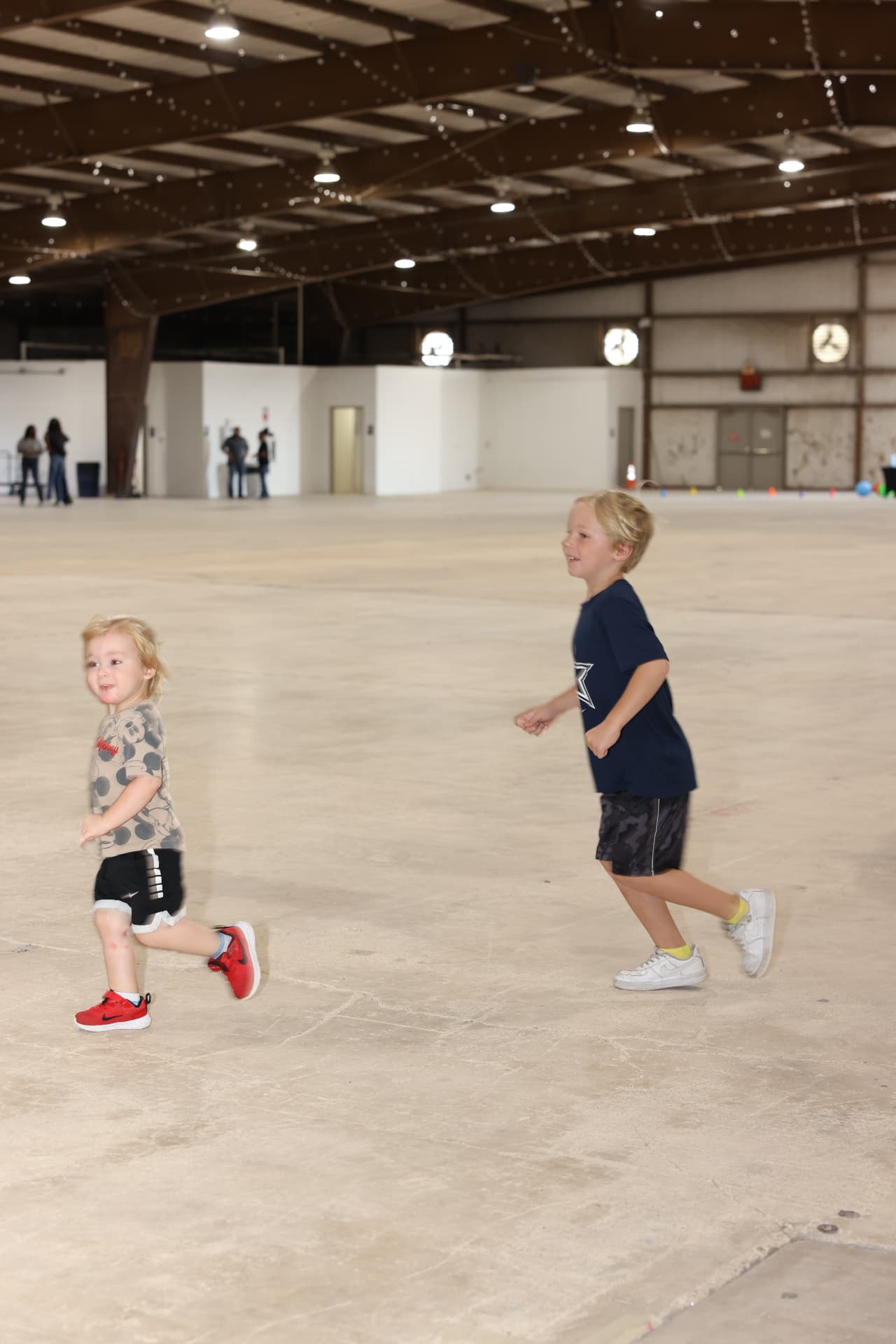 Two young boys running and playing across the venue floor.