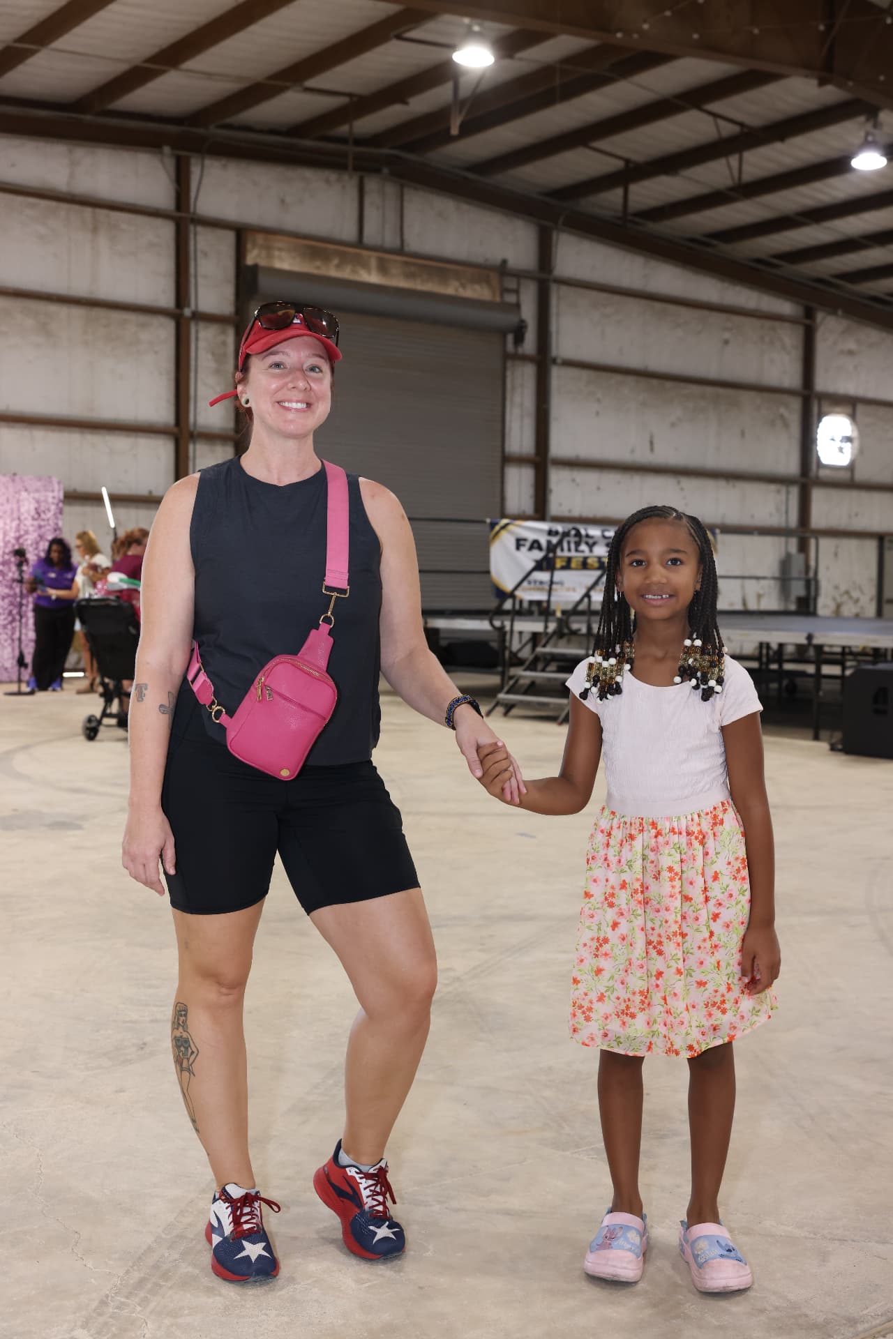 A volunteer holding hands with a young girl in front of the festival banner.