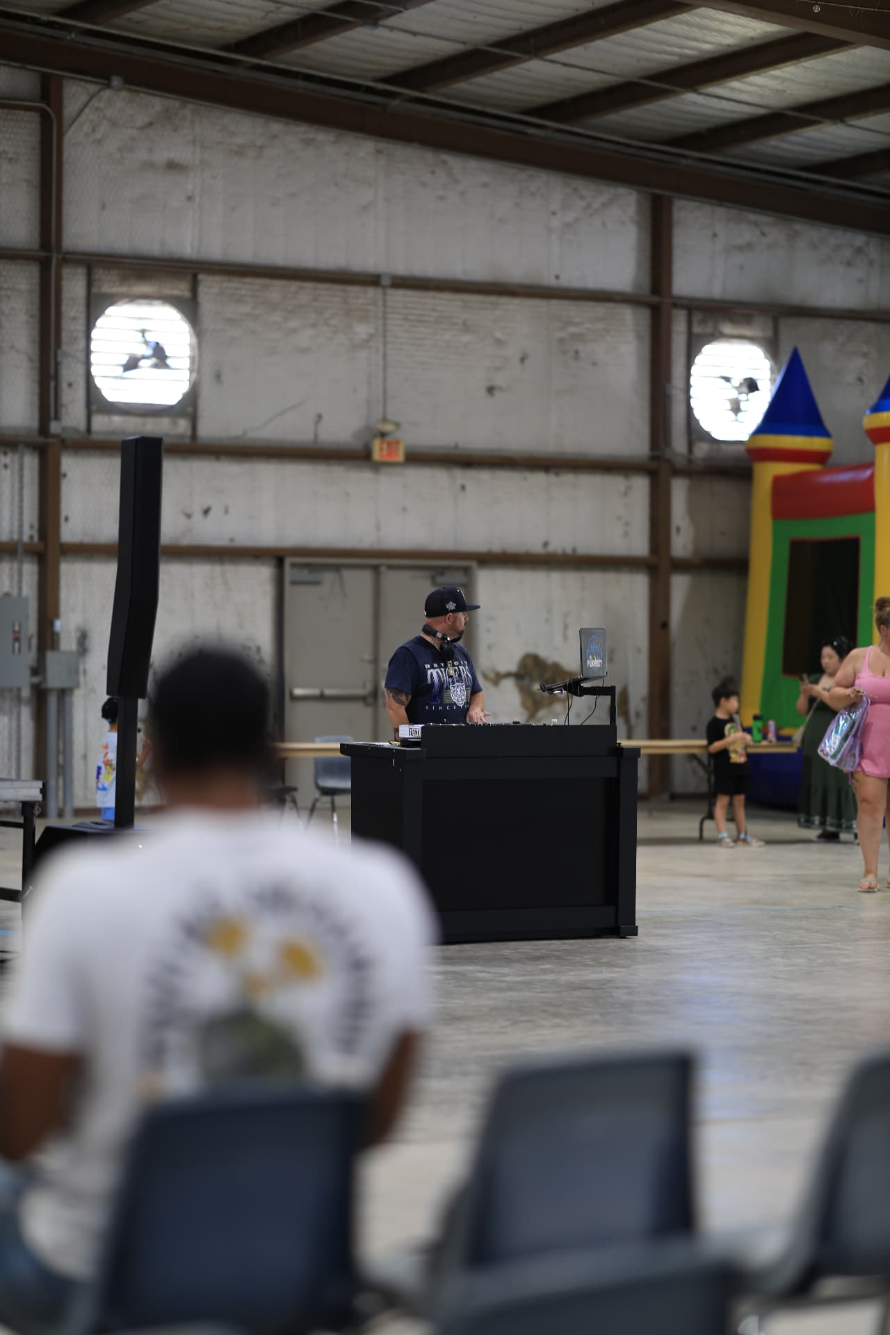 DJ PlayBizy spinning music beside the bounce houses inside the venue.