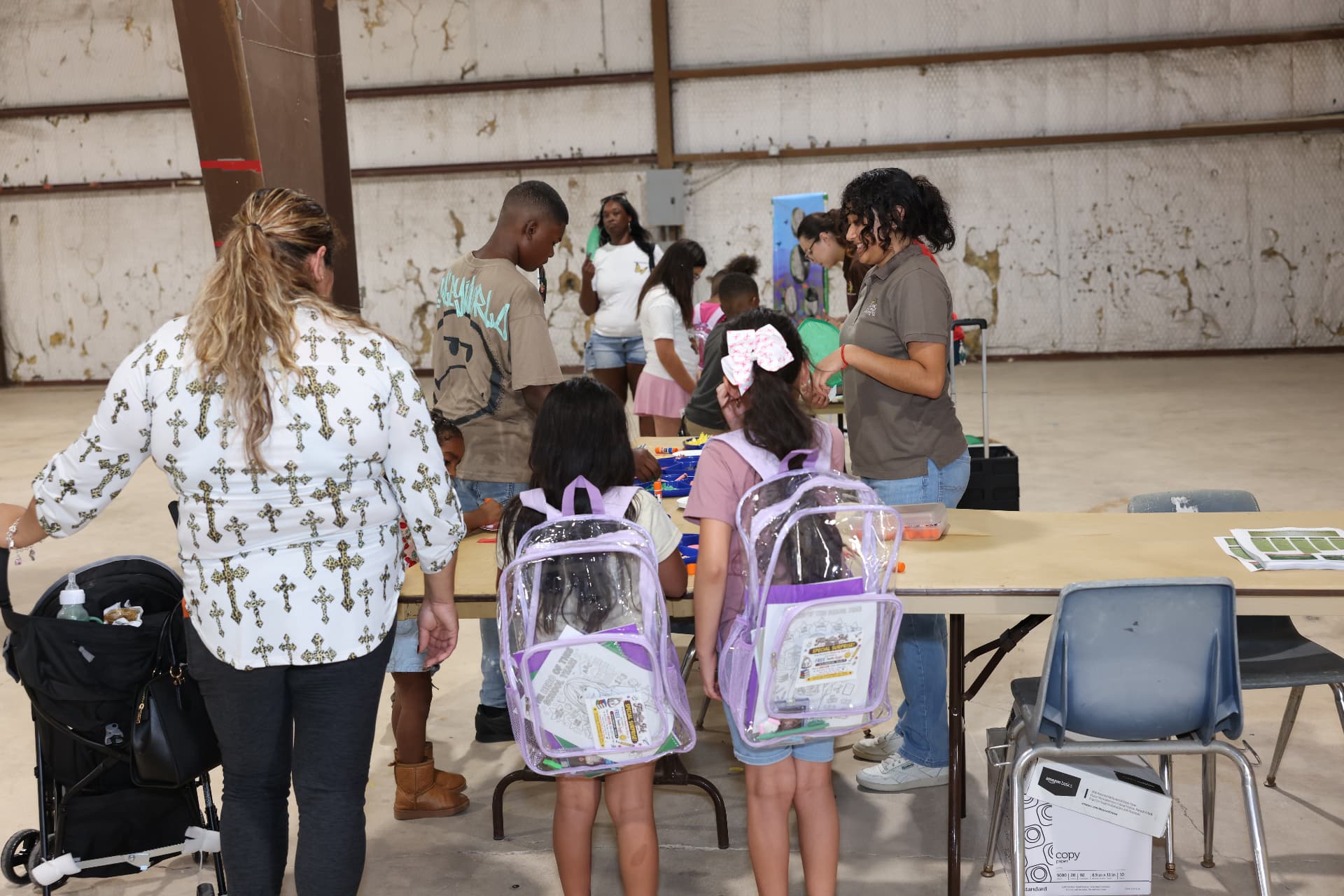 Children with clear backpacks working on crafts at an activity table.