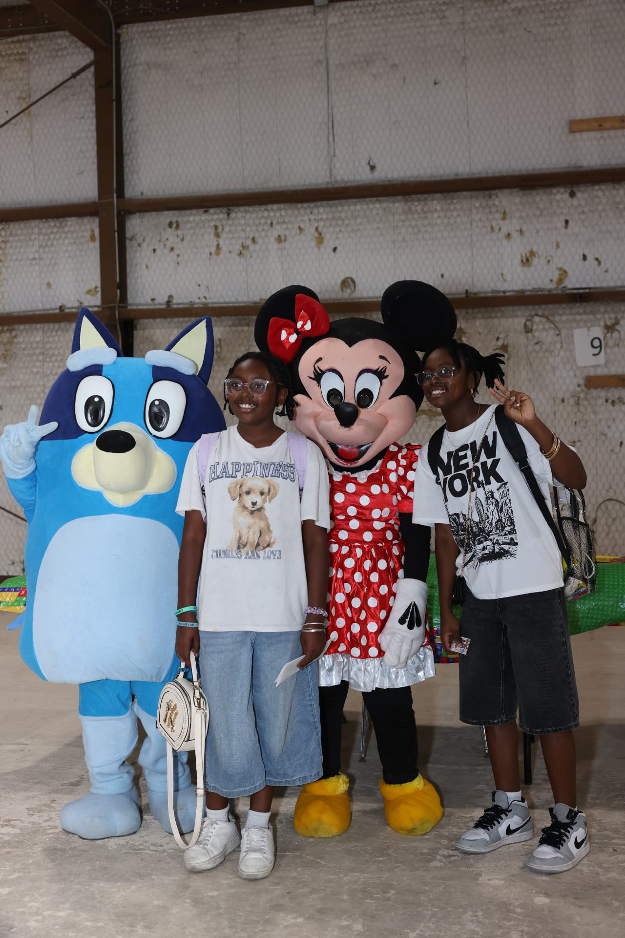Two teens posing with the Bluey and Minnie Mouse mascots.
