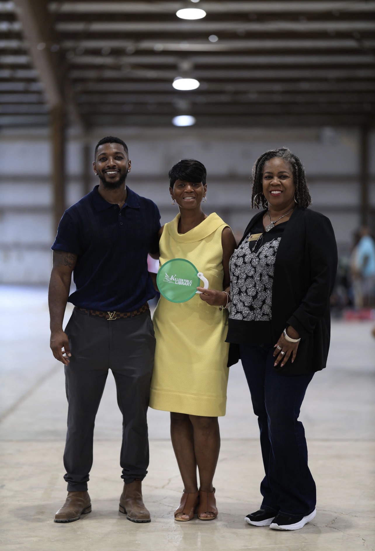 The festival organizer with two Killeen Public Library staff members holding a library fan.