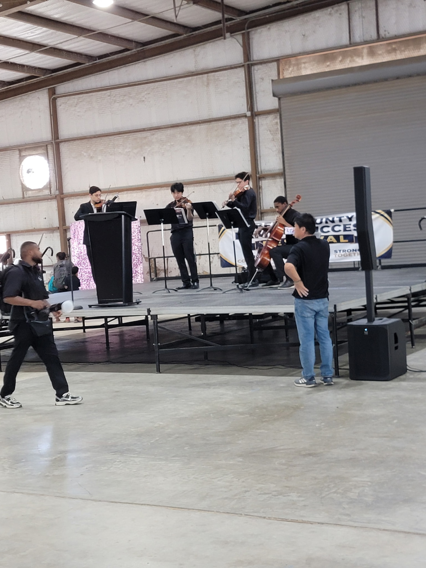 The string quartet playing as staff coordinate the program near the stage.