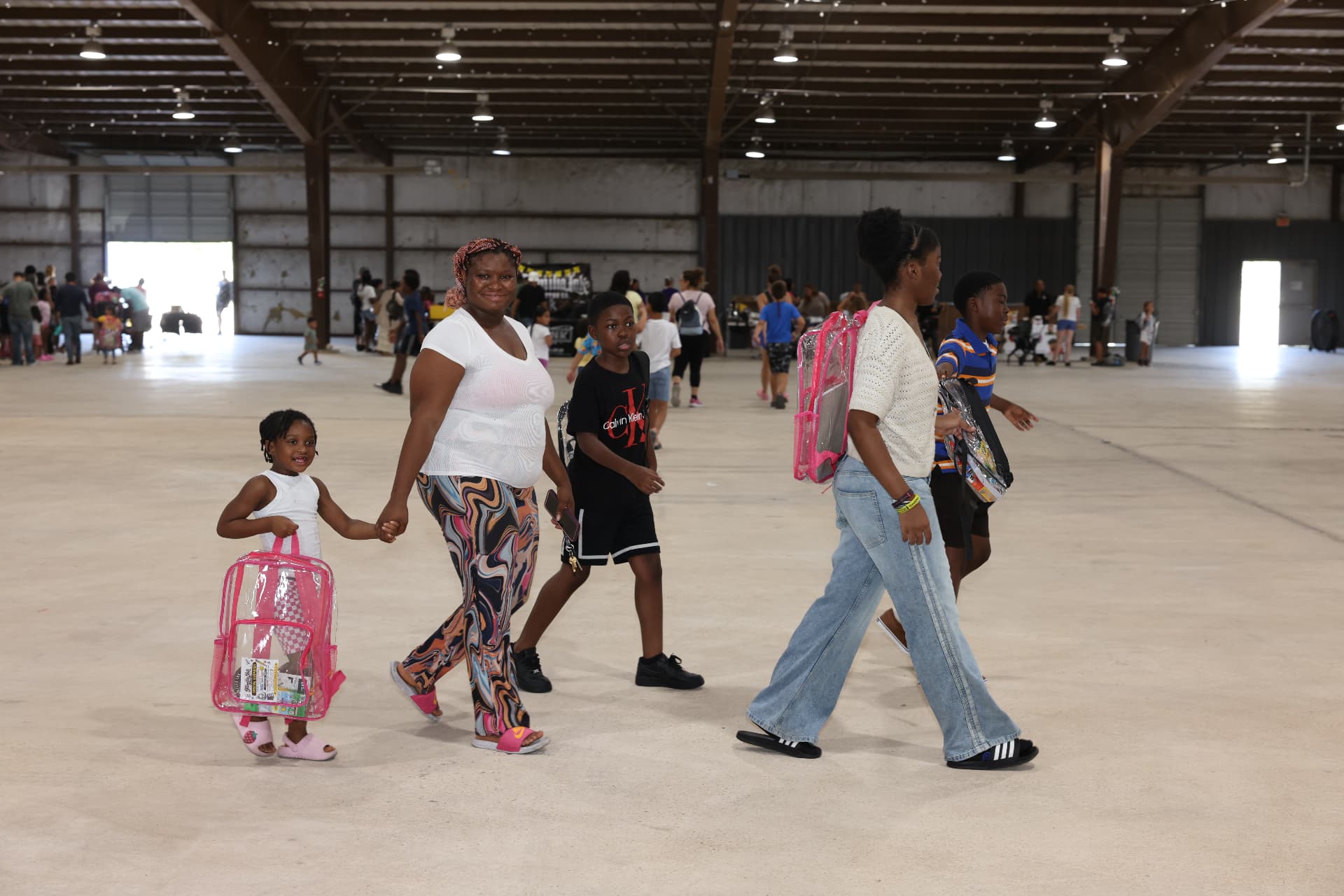 A family walking through the venue carrying clear backpacks.